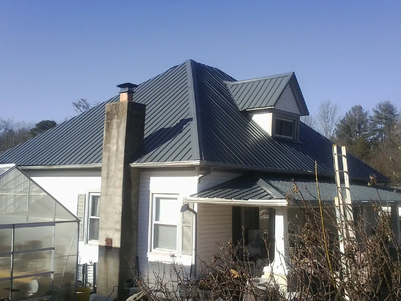Dark blue standing seam metal roof on a white farmhouse with dormer — Slate & Tile Roof Repair by Roofing Brothers in Keswick