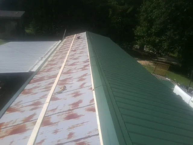 Old rusted panels beside newly installed green metal roofing — Wind Damage Roof Repair by Roofing Brothers in Keswick