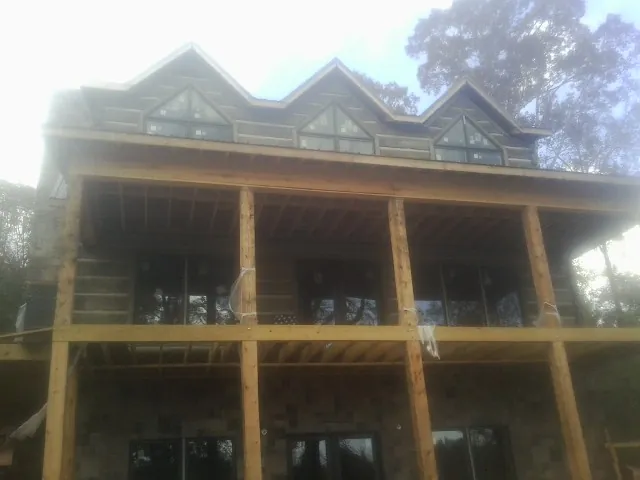 Dormers and porch framing on a large log home under construction — Roof Coating work by our crew in Keswick