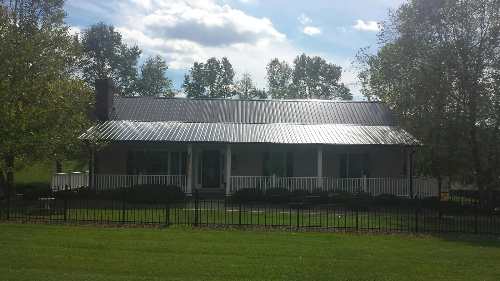 Gray metal roof on a brick ranch with a full width front porch — Gutter Guard Installation work by our crew in Keswick
