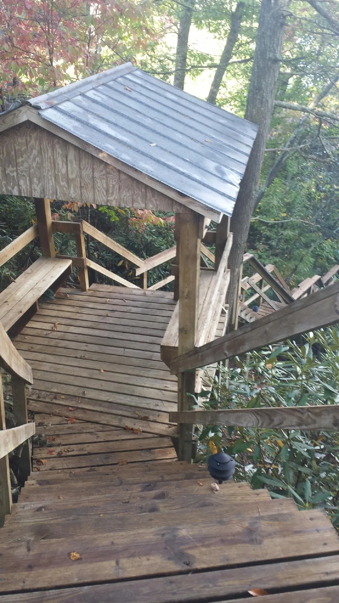 Metal roofed shelter over wooden steps on a wooded walkway — Skylight Repair & Installation work by our crew in Keswick