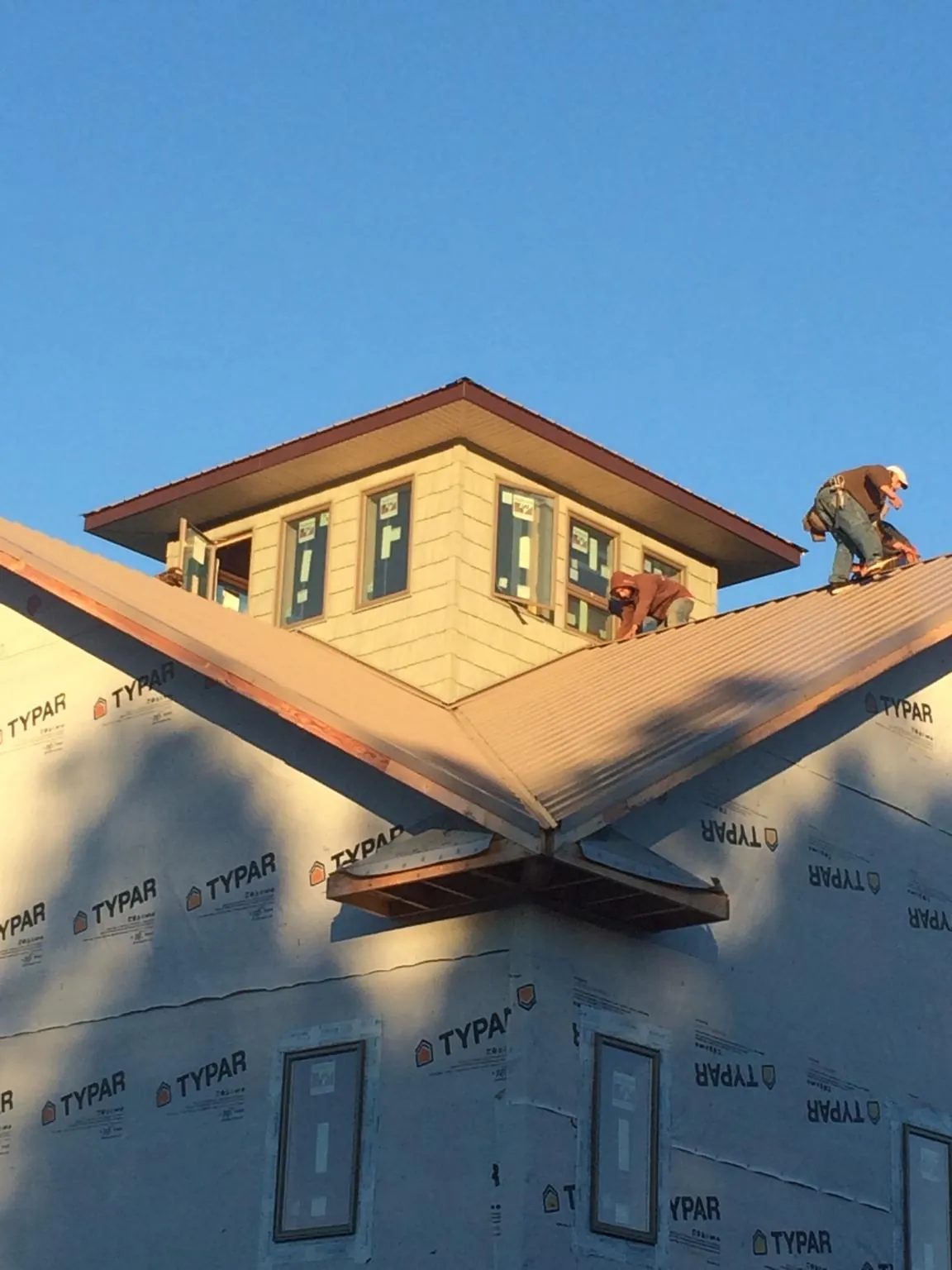 Roofers working around a rooftop cupola on a new metal roof at sunset — Roof Waterproofing in Keswick by Roofing Brothers